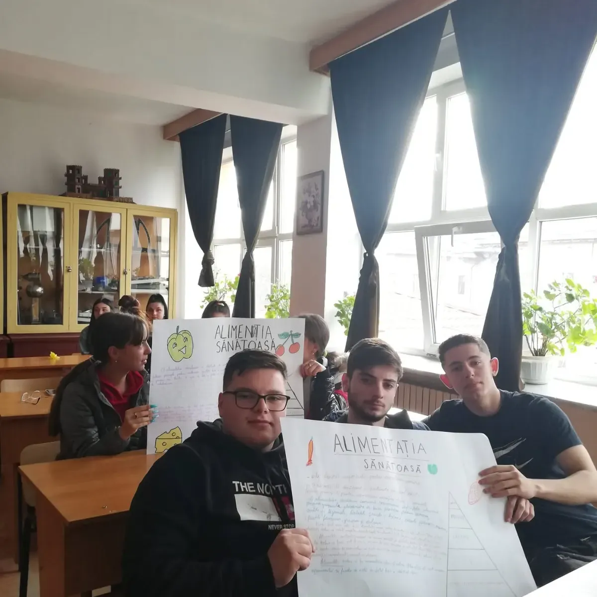 Elevi într-o sală de clasă prezentând postere despre alimentația sănătoasă